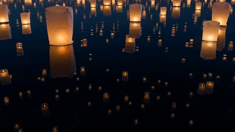 AI-generated video still from the prompt “hundreds of paper lanterns rising over a midnight lake, reflections shimmering on still water”