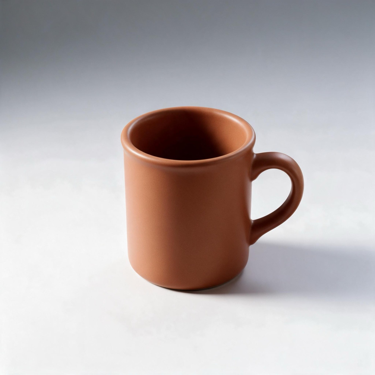 AI-edited terracotta mug on a seamless grey-to-white studio backdrop